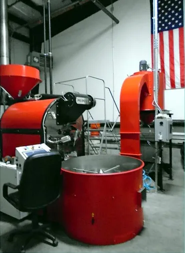 Red coffee roasting equipment under an American flag at the roastery